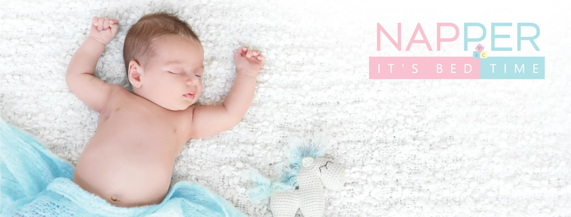 A newborn stretching out on a soft white blanket